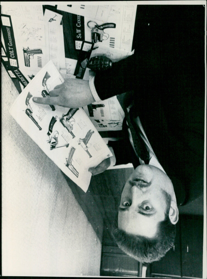 A Colt Government Model 1911 handgun is pictured with several other pistols. - Vintage Photograph