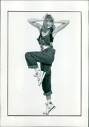 A model showcases a fashionable ensemble consisting of black denim dungarees and a copper sequin bra top. - Vintage Photograph