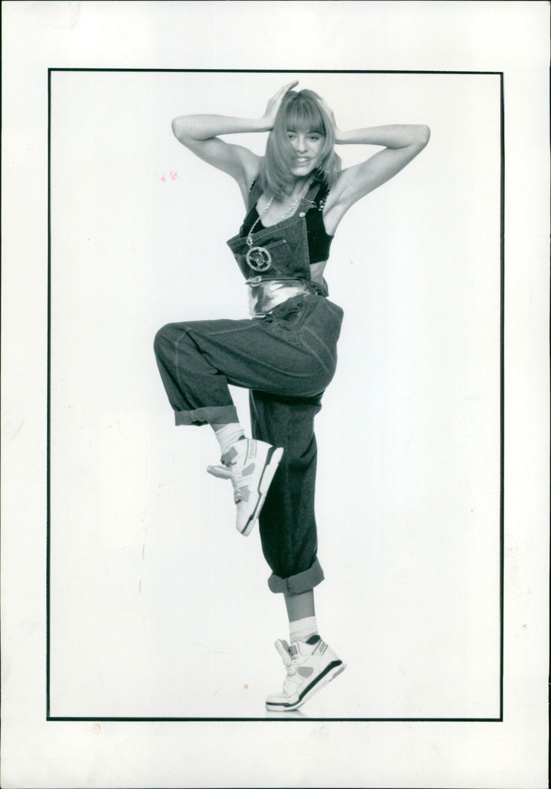 A model showcases a fashionable ensemble consisting of black denim dungarees and a copper sequin bra top. - Vintage Photograph