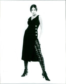 A model showcases a pair of harlequin-patterned opaque tights from Colture Designer Hosiery. - Vintage Photograph