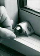 A patio door push lock is being installed. - Vintage Photograph