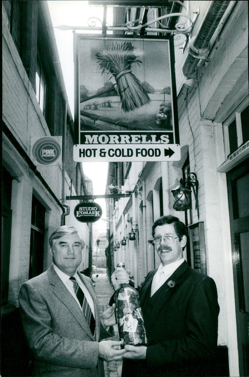 Mr Cliff Wilkinson, headmaster of Northfield School, presents a charity bottle to Mr Bob Ansell, manager of the Wheatsheaf pub. - Vintage Photograph