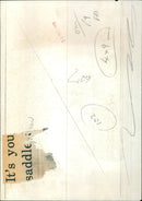 A young Afghan boy in traditional attire riding a donkey near a village. - Vintage Photograph