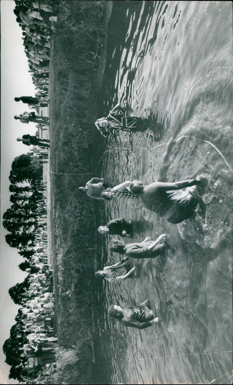 A man stands on a small boat in a river, illuminated by a flash of light. - Vintage Photograph