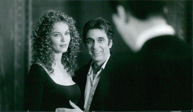 In this iconic image from the 1997 film "The Devil's Advocate", Al Pacino and Keanu Reeves are seen in conversation with Connie Nielson. - Vintage Photograph