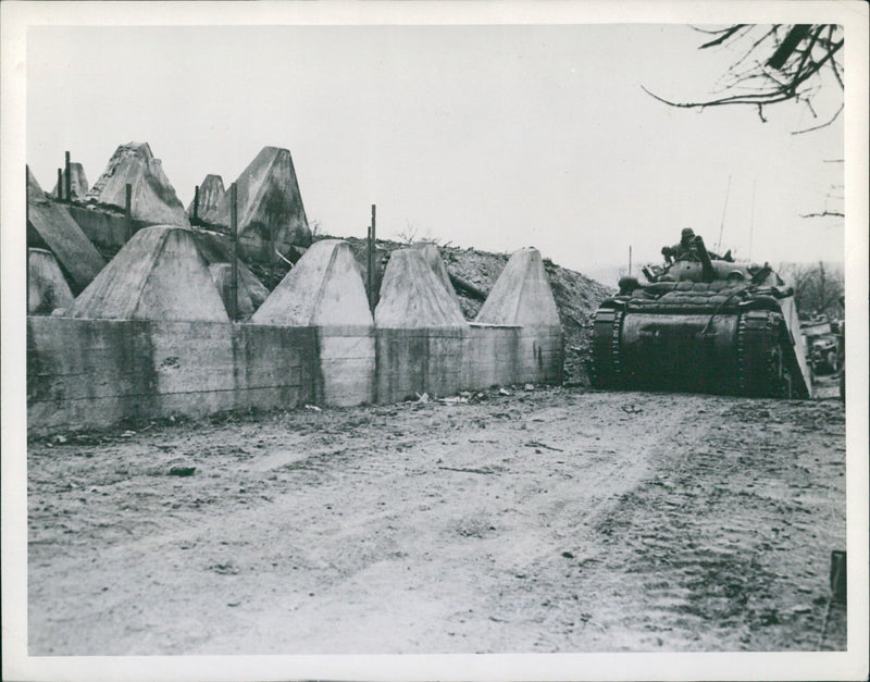 U.S. tank advances past a concrete tooth of the Siegfried Line in Germany on March 20, 1945. - Vintage Photograph