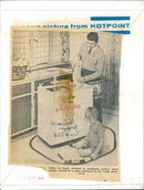 A father plays with a model train while his son looks on. - Vintage Photograph