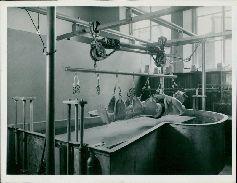 Dr. J.B. Stewart of the Swindon Hospital Management Committee Physiotherapy Department demonstrates modifications to a Hubbard Tank for patients with poliomyelitis or spastic paralysis. - Vintage Photograph