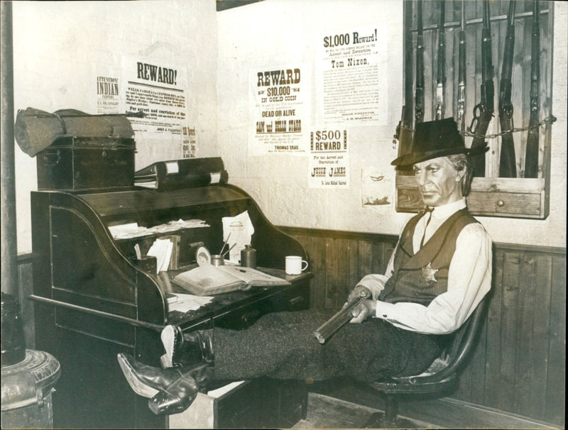 A model of famous screen lawman Gary Cooper keeping watch on a jailhouse set at the Palladium Cellars tourist attraction in London. - Vintage Photograph