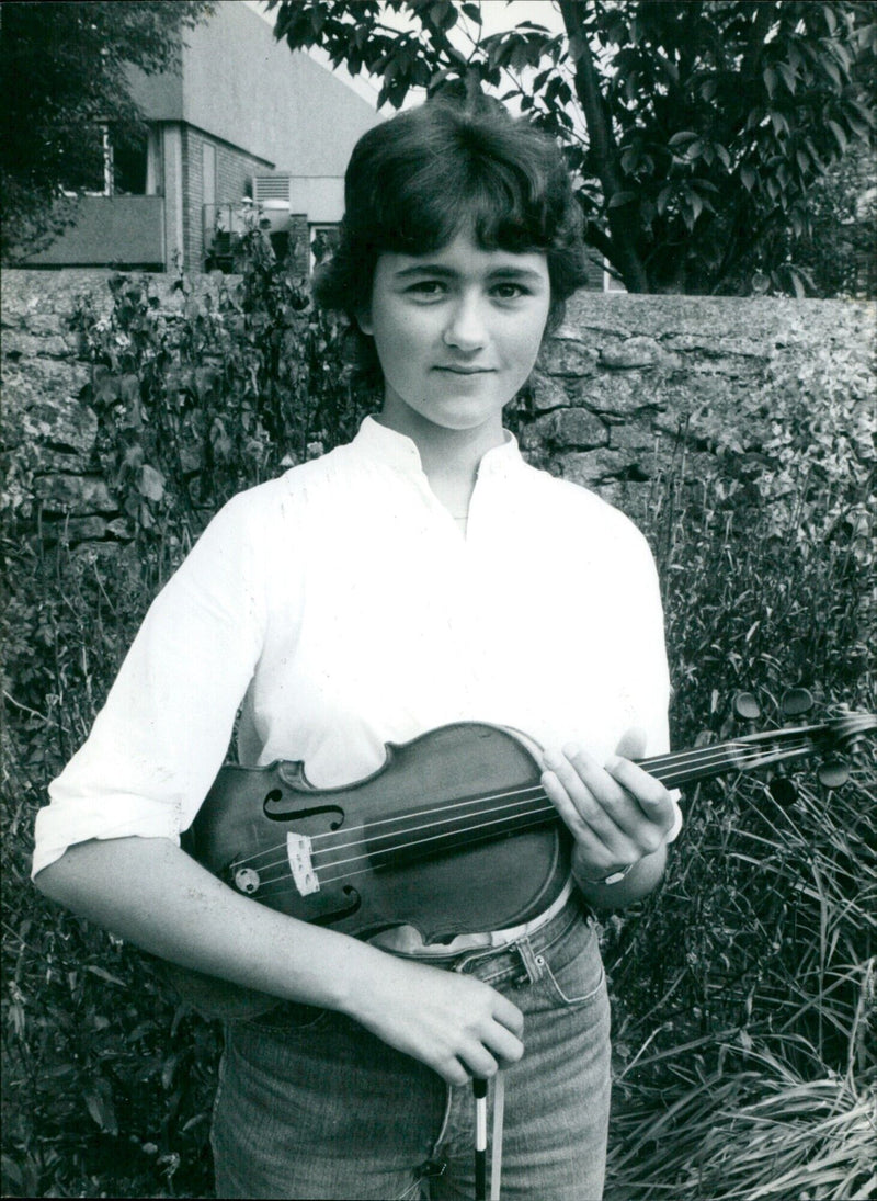 A young musician plays guitar in a city park, despite the cold weather. - Vintage Photograph