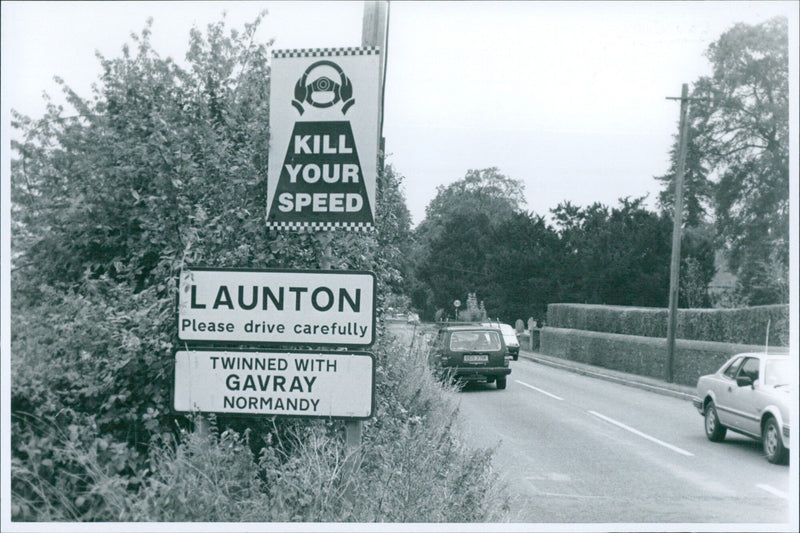 A sign reading "KILL YOUR SPEED" stands in a rural landscape in Launton, England. - Vintage Photograph