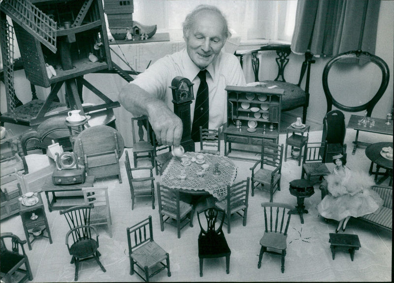 A miniature hobby enthusiast perfects a model house. - Vintage Photograph
