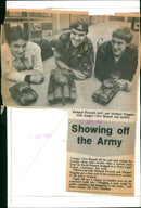 Fifteen-year-olds Richard Peverell and Michael Huggins inspect scaled-down models of heavy weapons alongside Army Trooper Clive Russell. - Vintage Photograph