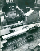Two-year-old Christopher Booth tries on a train driver's cap at the Abingdon Model Railway Club show. - Vintage Photograph