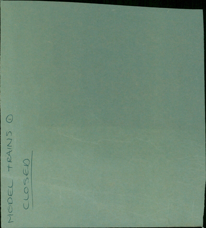 A man holds a model train set inside a closed Avery Ⓡ Manilla Folder. - Vintage Photograph