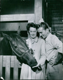A man is seen taking a photograph with an old-fashioned film camera while standing in front of a scenic cityscape. - Vintage Photograph