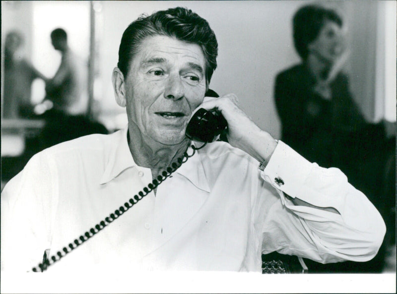 President Ronald Reagan making a phone call from an hotel in Los Angeles while tieless and in shirtsleeves. - Vintage Photograph