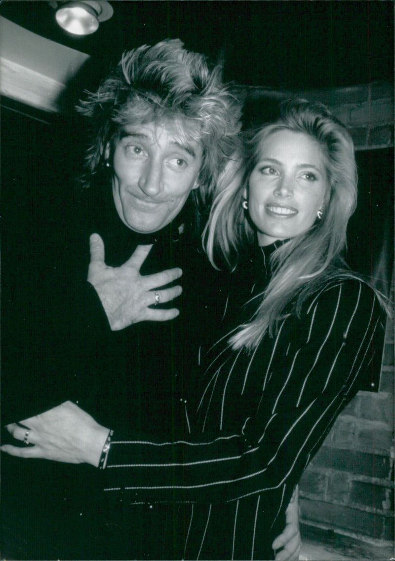 British pop stars Rod Stewart and Kelly Emberg pose together in 1989. - Vintage Photograph