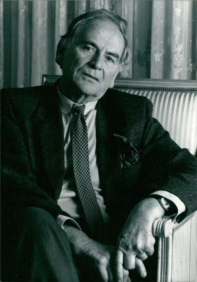 French fashion designer, Pierre Cardin, poses in his Paris studio in 1988. - Vintage Photograph