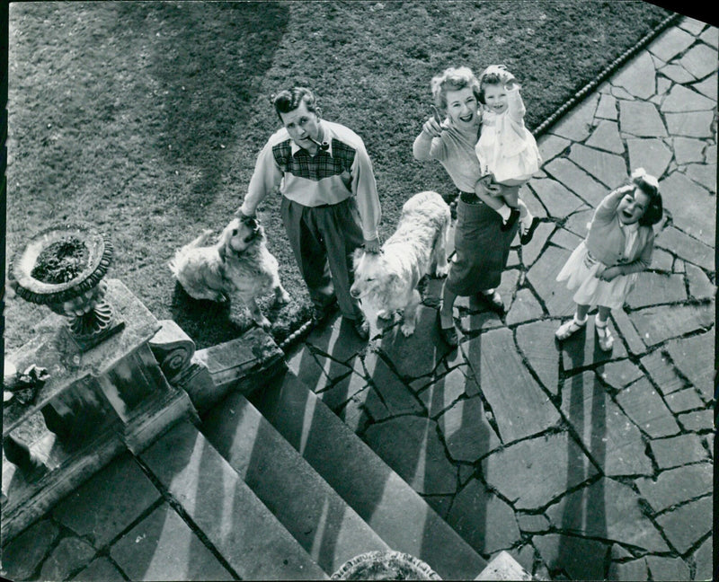 The Braden family of four, Bernard, Barbara Kelly, Kim and Kelly, pose with their two golden retrievers at home. - Vintage Photograph