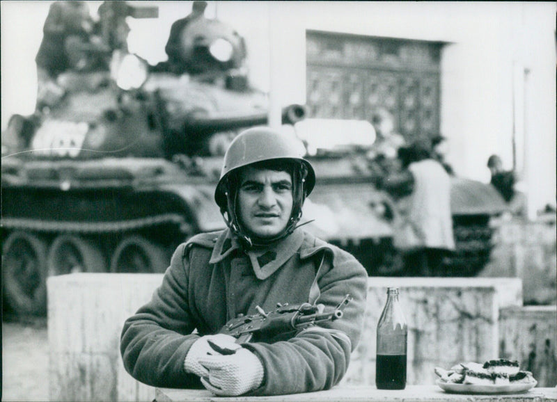 A Romanian soldier with a machine gun and a cake at the ready during the revolution of December 1989 in Timisoara, Romania on December 23rd. - Vintage Photograph