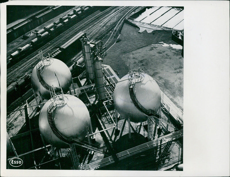 Workers inspect a storage tank at an oil field in the U.S.A. - Vintage Photograph