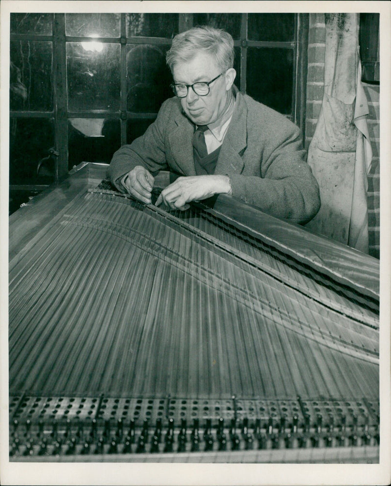 Musician Robert Gossa checking the tuning of a Marpsichord. - Vintage Photograph