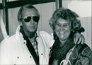 Paul Hogan, star of the film "Crocodile Dundee", poses with his wife in 1987. - Vintage Photograph