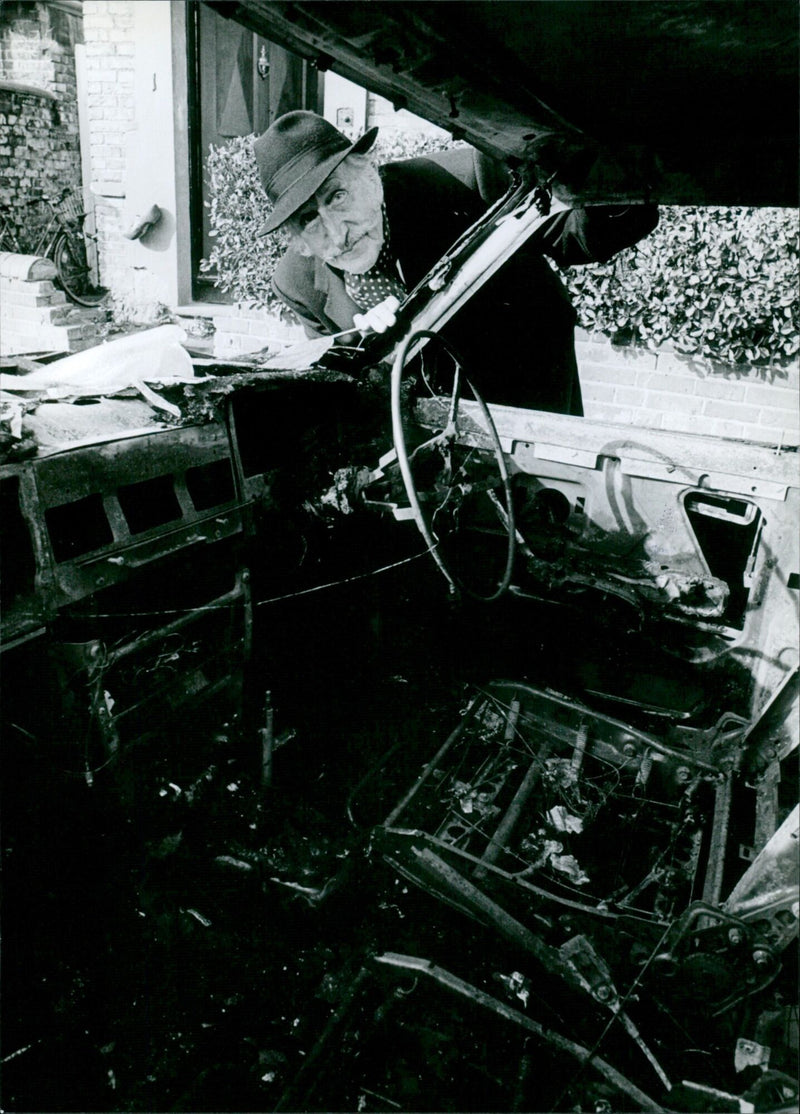 Robert Branch stands next to his burnt-out Volvo in Cripley Road on March 10, 1992. - Vintage Photograph