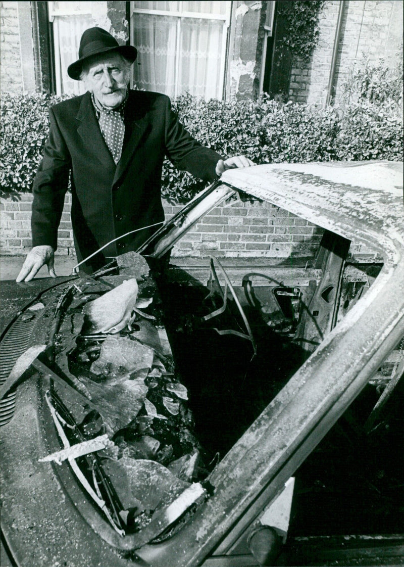 Robert Branch stands next to his burnt out Volvo in Oxford, England. - Vintage Photograph