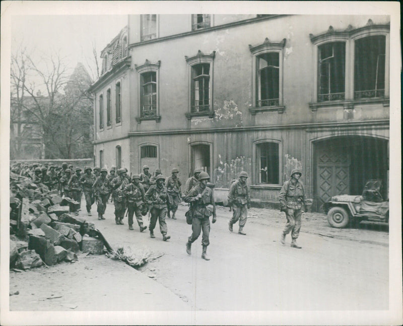 U.S. troops advance out of the German town of Zweibrucken after its capture on March 20, 1945, as part of the Seventh Army's push to link up with Third Army units west of Kaiserslautern, Germany. - Vintage Photograph