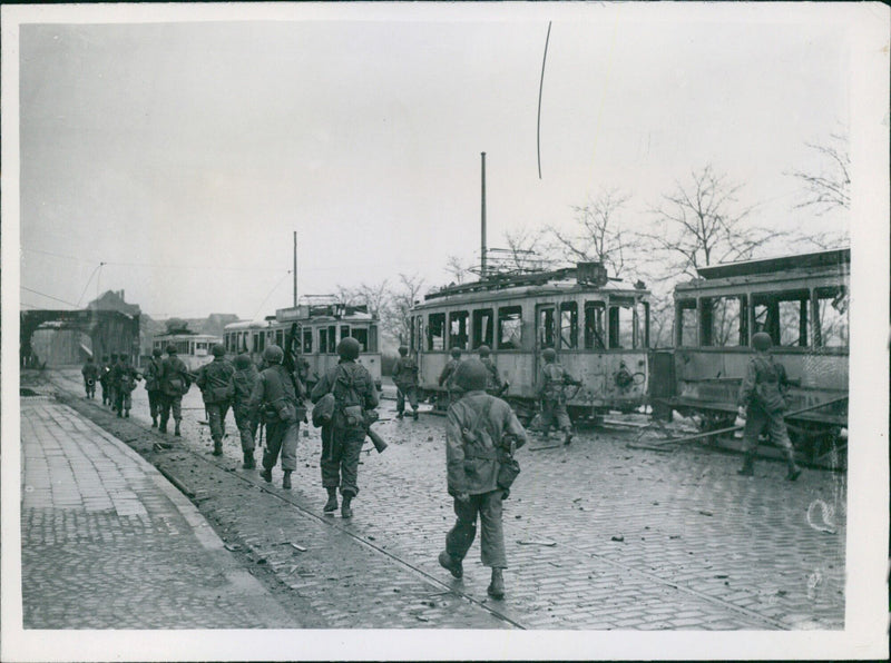 U.S. troops of the Ninth Army march through the city of Duisburg, Germany on March 27, 1945 as they liberate the city and its strategic port. - Vintage Photograph