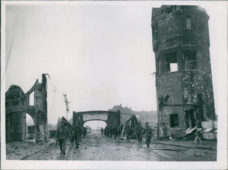 US troops of the Ninth Army cross a bridge in Duisburg, Germany, on March 27, 1945, during a drive eastward from the Rhine River. - Vintage Photograph