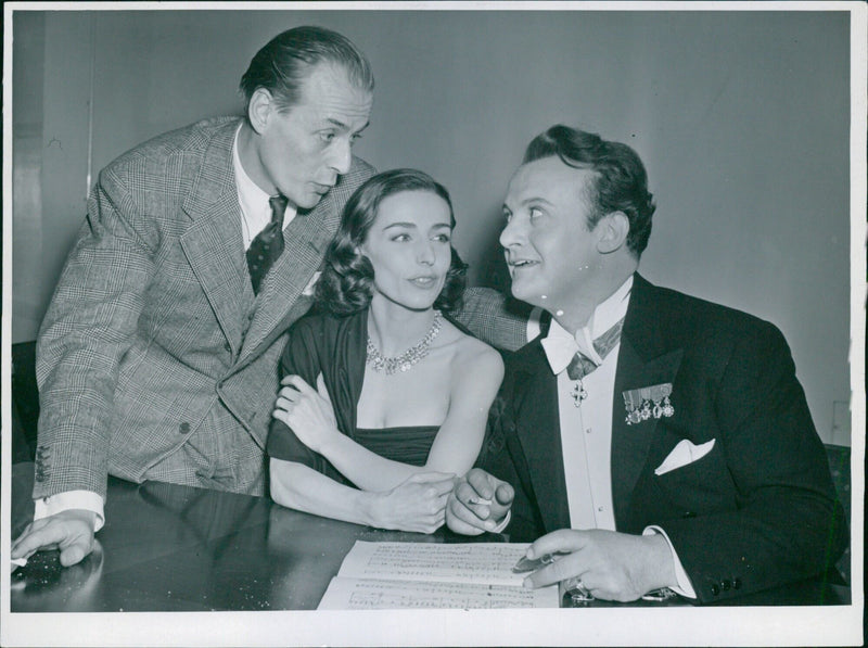 Actors Hasse Ekman, Ellen Rasch, and Tito Gobbi enjoy a comedic conversation during a film shoot at the Royal Opera House in Stockholm, Sweden on February 29, 1959. - Vintage Photograph