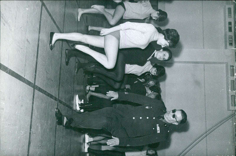 Two people stand in front of a building, one holding a sign that reads "10, Avenue Fro Paris (7)" in Arabic. - Vintage Photograph