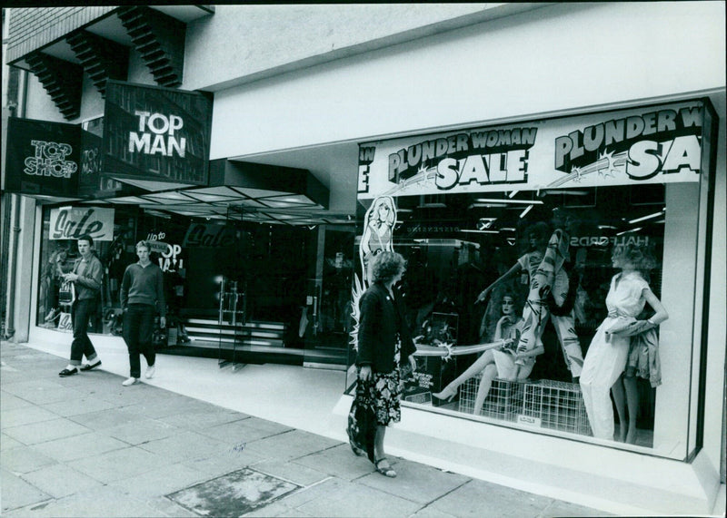 A woman and a man pose for a photograph at a Sale Plunder store. - Vintage Photograph