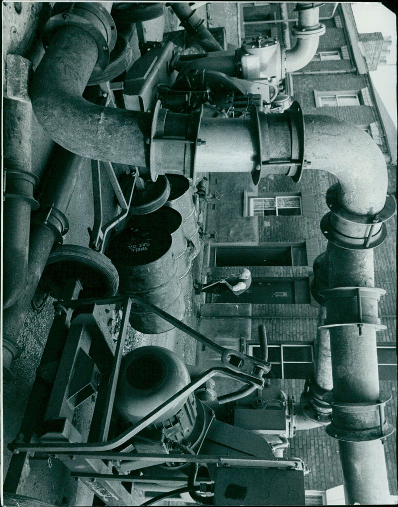 A man stands beside a Shell Gas Oil fuel pump. - Vintage Photograph