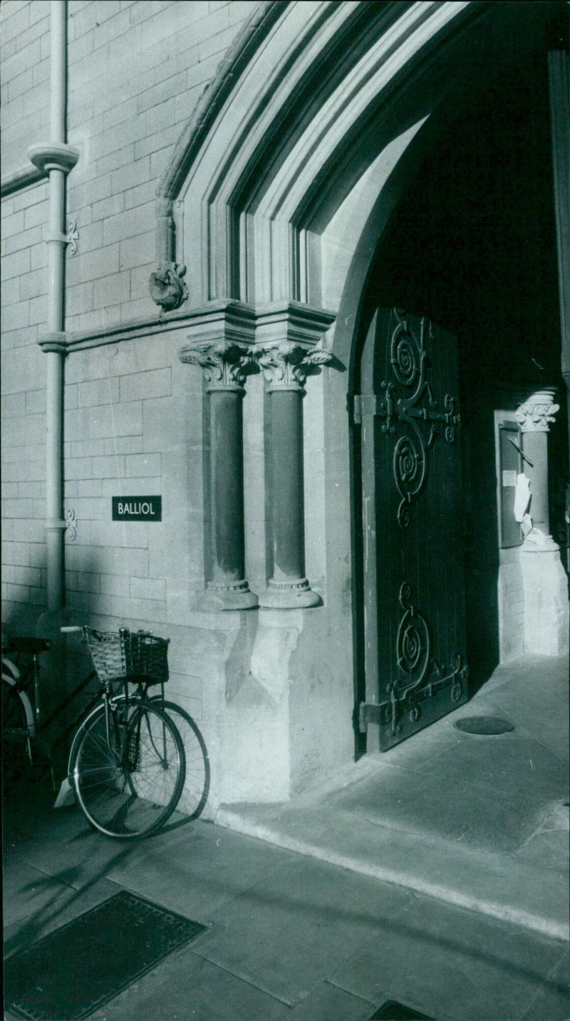 A student plays with a large beach ball in front of Balliol College in Oxford, England. - Vintage Photograph