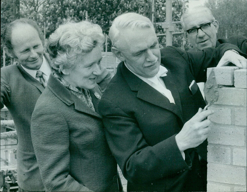 Construction workers and other attendees celebrate a topping-out ceremony for a building. - Vintage Photograph