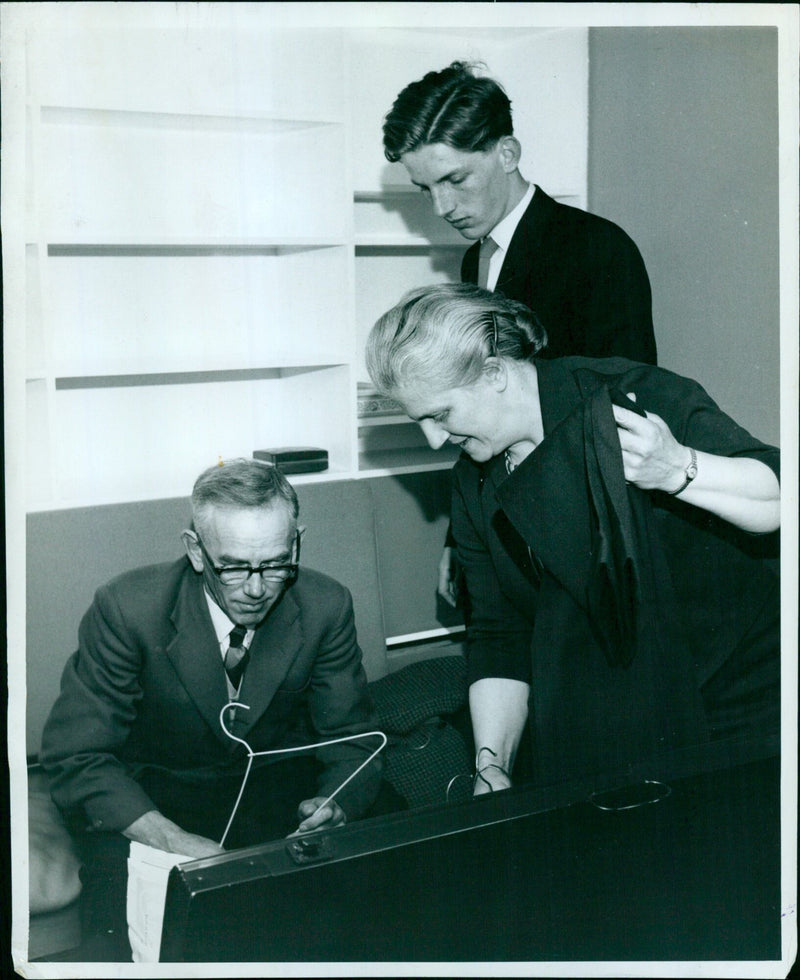 Mr. and Mrs. A.E. Hand assist their son, Robin, as he unpacks his belongings in his room at St. Catherines College. - Vintage Photograph