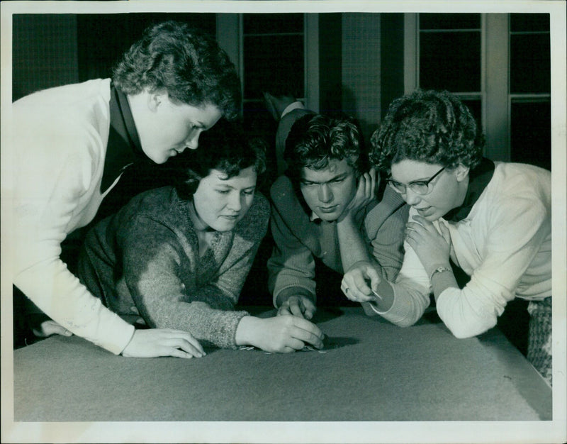 Three Oxford University students watch as a fourth student squidges a wink. - Vintage Photograph