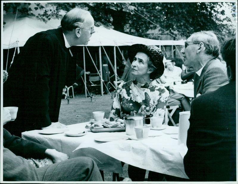 The Warden of Keble College, the Rev. Dennis Nineham, chats with the Rev. and Mrs. J.G. Grimswade at a garden party in the college grounds. - Vintage Photograph