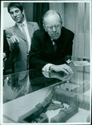 Peter Ahrends and Rev Dennis Nineham examine a model of Keble College. - Vintage Photograph