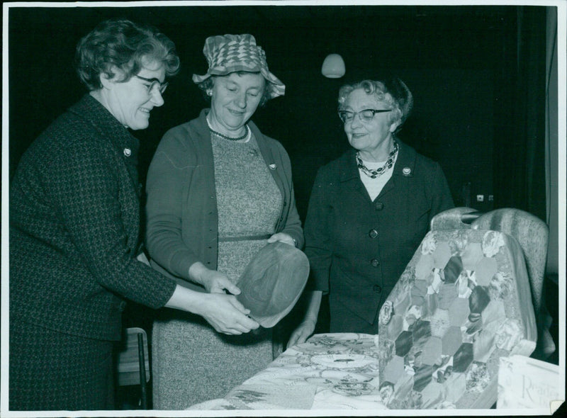 Mrs. G. Watts, Mrs. A. Ames, and Mrs. E. Lyon Cowly look at handicrafts. - Vintage Photograph