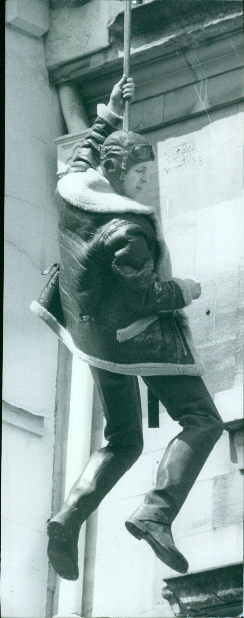 A stuntman performs a daring jump off a high platform during a show in an unidentified location. - Vintage Photograph