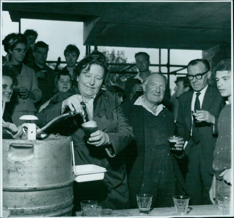 Dr. K. Vernyon, Principal of St. Hughes College, pours beer for the workmen on the site. - Vintage Photograph