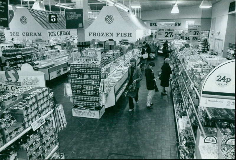 A variety of food items including ice cream, fish, cookies, and spices are displayed in a supermarket. - Vintage Photograph