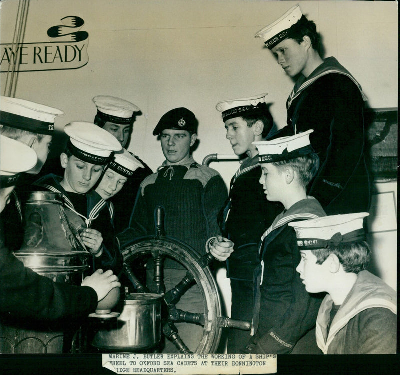 Marine J. Butler explains the working of a ship's wheel to Oxford Sea Cadets. - Vintage Photograph