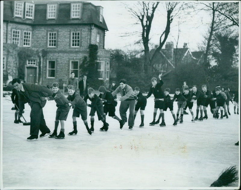 J. C. Marshall, an international rugger player and master at Dragon School, pulls Nong on a skates line made by flooding their school's remains. - Vintage Photograph