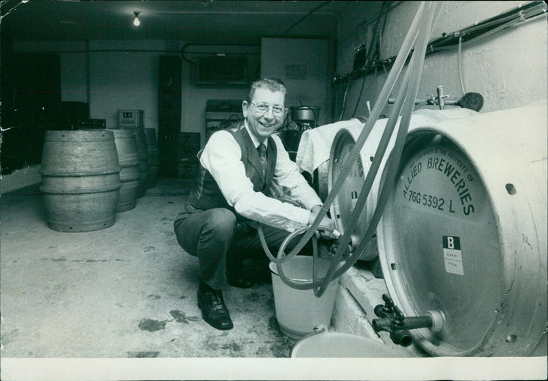 Employees of a brewery prepare a large barrel of beer for storage. - Vintage Photograph